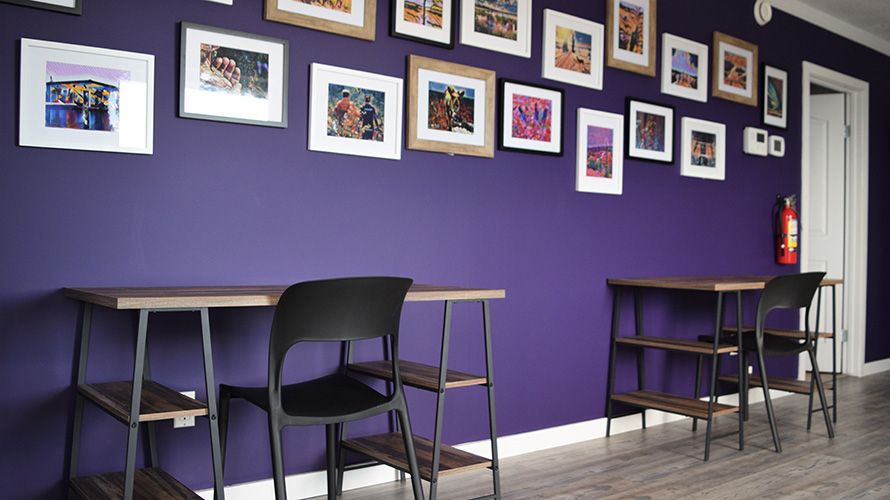 Two desks facing a purple wall decorated with a gallery of Laurier research and nature photos.