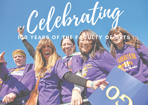 Students cheering towards the camera wearing Laurier t-shirts and hoodies, with decorative text "Celebrating 100 years of the Faculty of Arts"