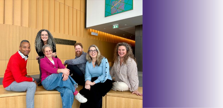 Three voice lab instructors leaning on a railing in the Savvas Chamberlain Music Building atrium