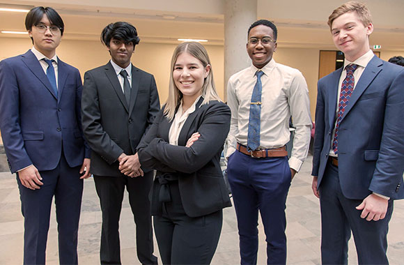 Five students pose with arms folded in front of them.