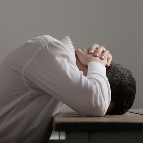 Person with head on a table looking stressed