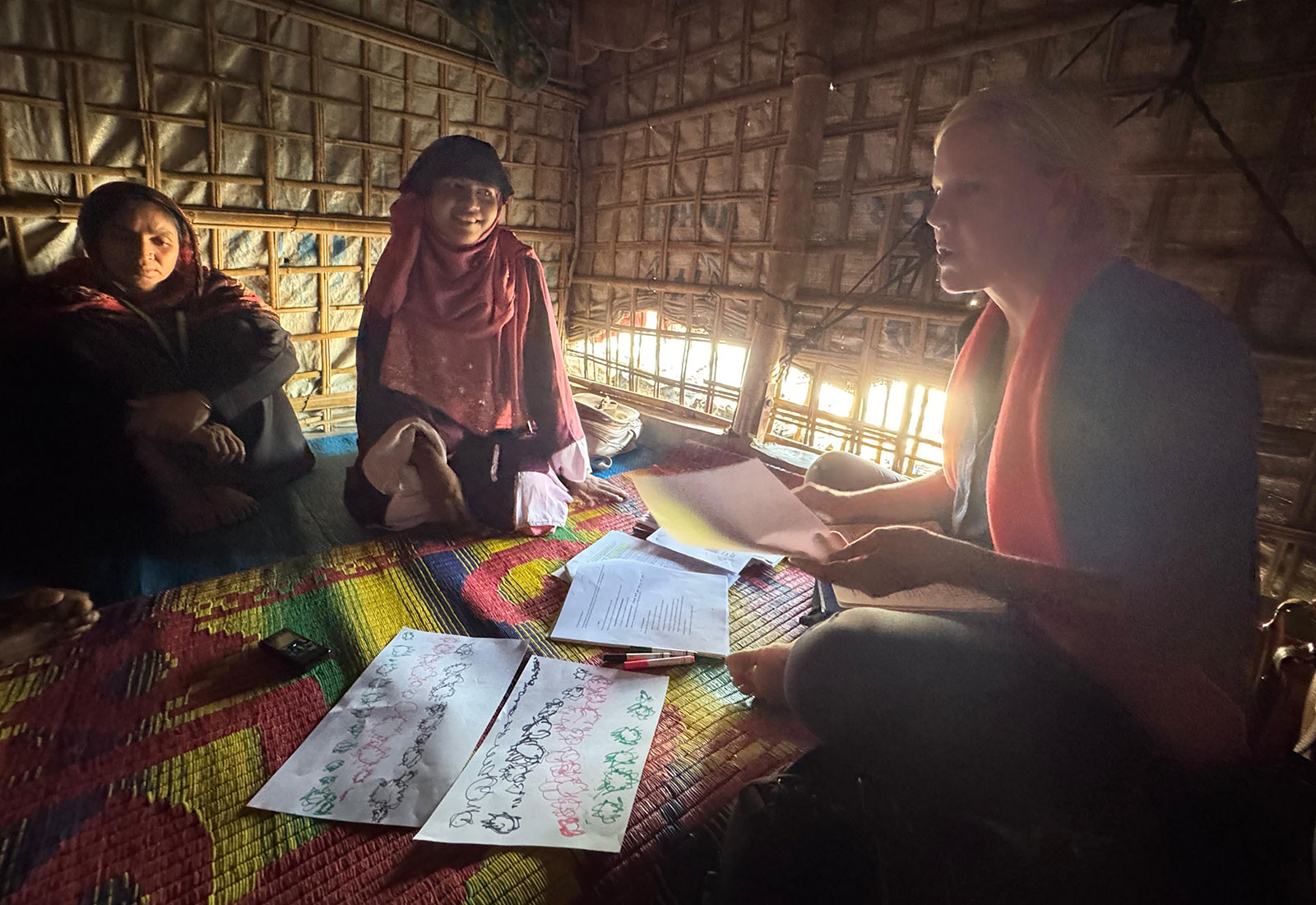 Bree Akesson sitting in hut speaking to research participants