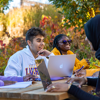 Students sitting outside with laptops