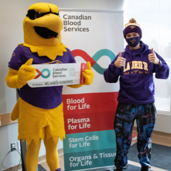 Golden Hawk mascot standing beside a male student.