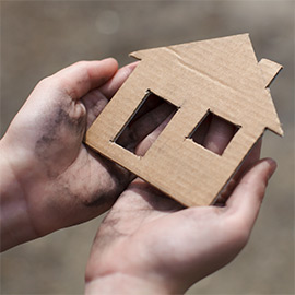 Hands holding cardboard cut out of house