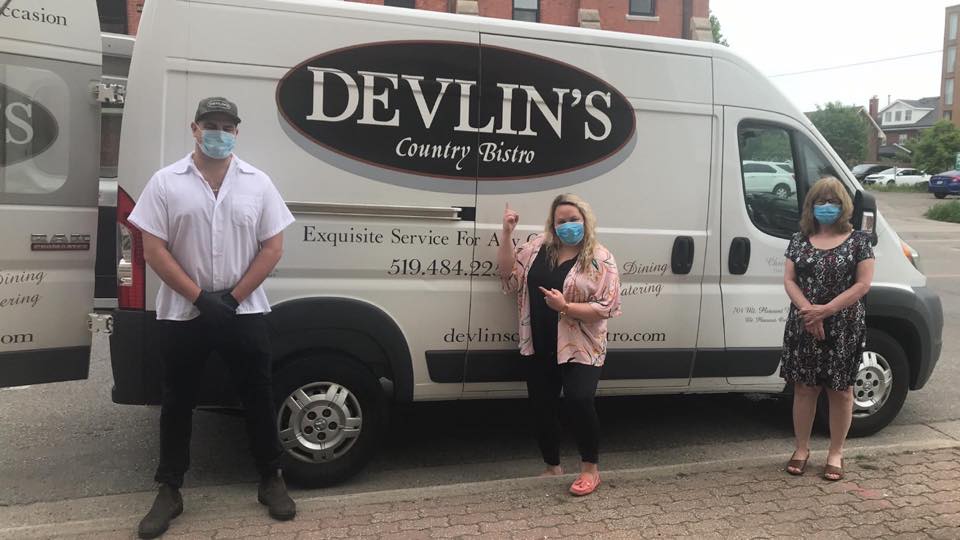 Three people stand in front of a food delivery truck