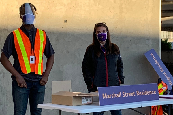 Two people standing behind a table wearing masks