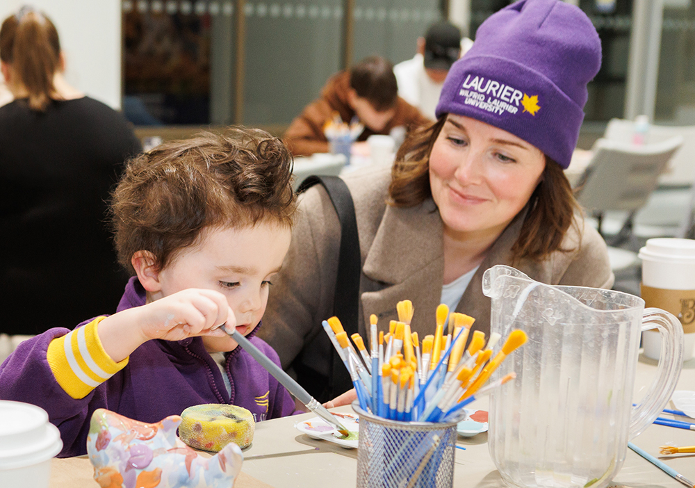 A child paints at the Purple and Gold Party's Crock a Doodle station