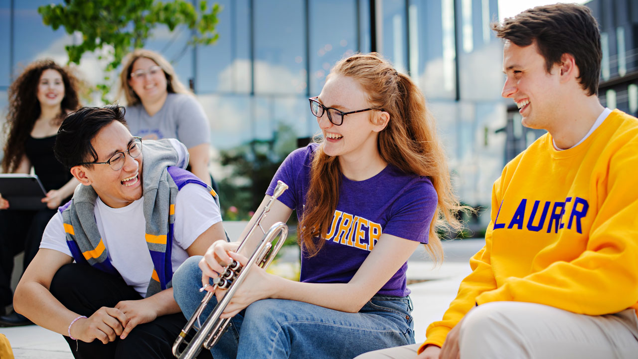 group of music students laughing in front of music building